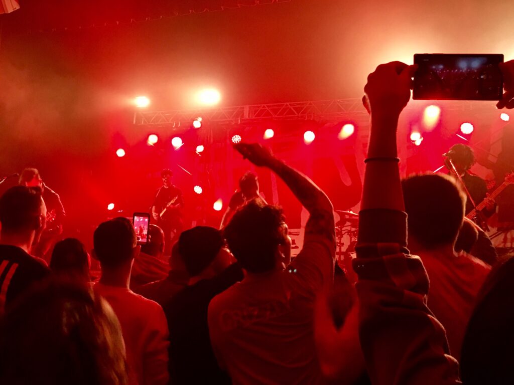 Fans jubeln bei einem Konzert und halten Handys in die Höhe