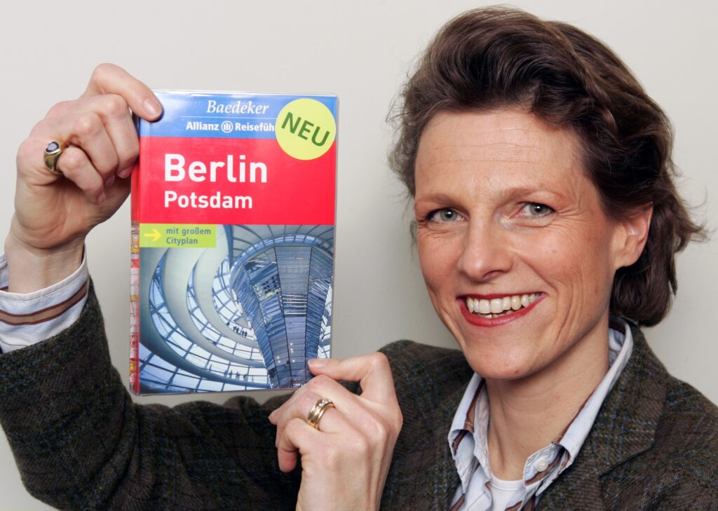Stephanie Mair-Huydts hält einen Reiseführer von Berlin in die Kamera und lächelt dabei