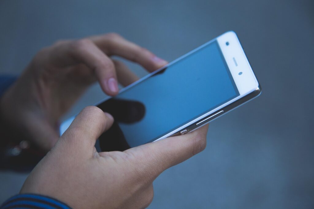 Ein Smartphone mit einer verschwommenen Chat-Nachricht neben Eheringen symbolisiert die Geschichte von Katharina Eisenblut nach dem Betrug in ihrer Ehe – Foto: Pexels / Pixabay