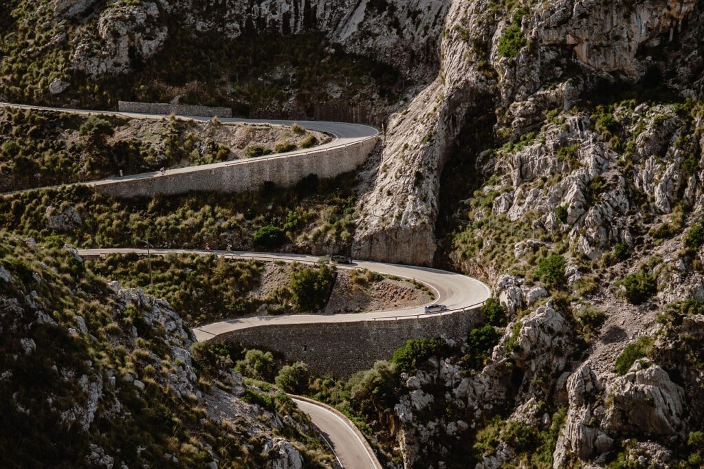 Ein Sportwagen steht am Rand einer kurvigen Bergstraße auf Mallorca, wo Klaus Rader tödlich verunglückte – Foto: mariya_m / Pixabay